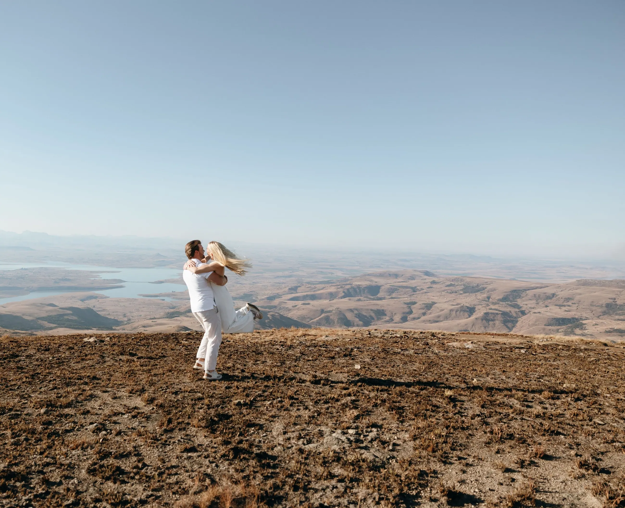 Joshua lifting Christy on the plateau, the dam and the valley far below
