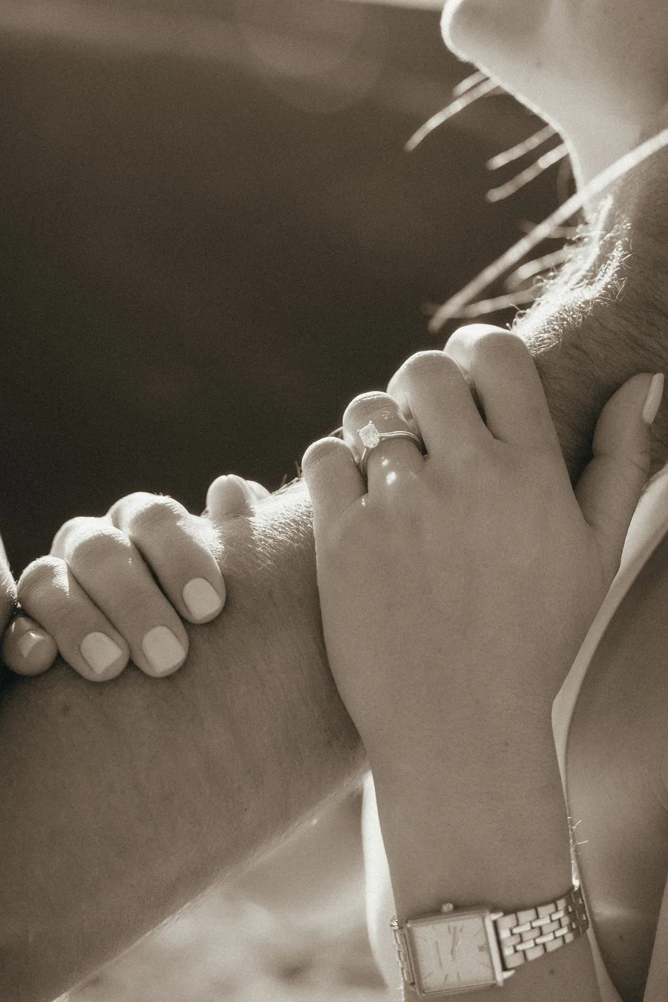 Their hands together on her shoulder, the ring catching the light