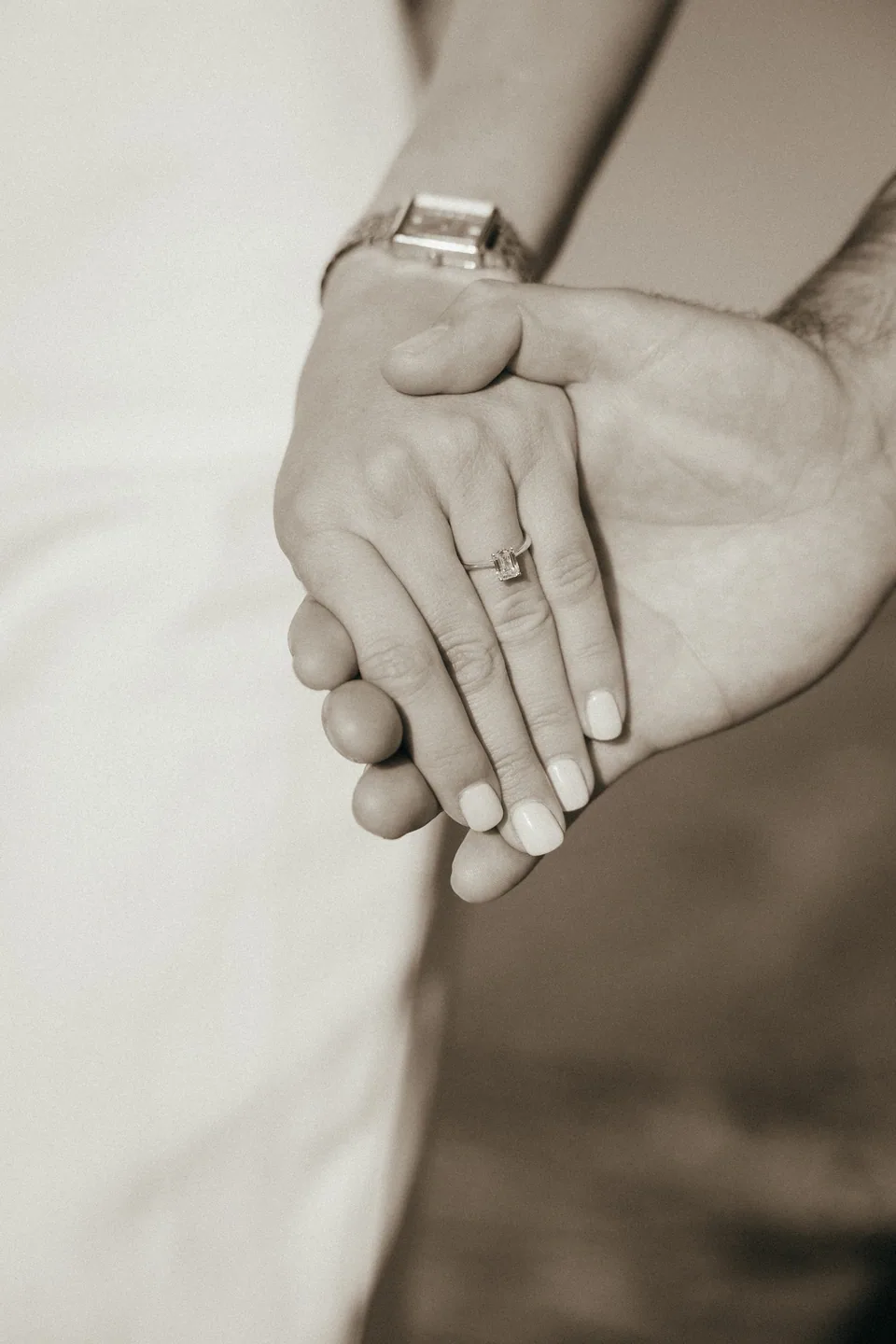 Her hand resting on his, the engagement ring in focus