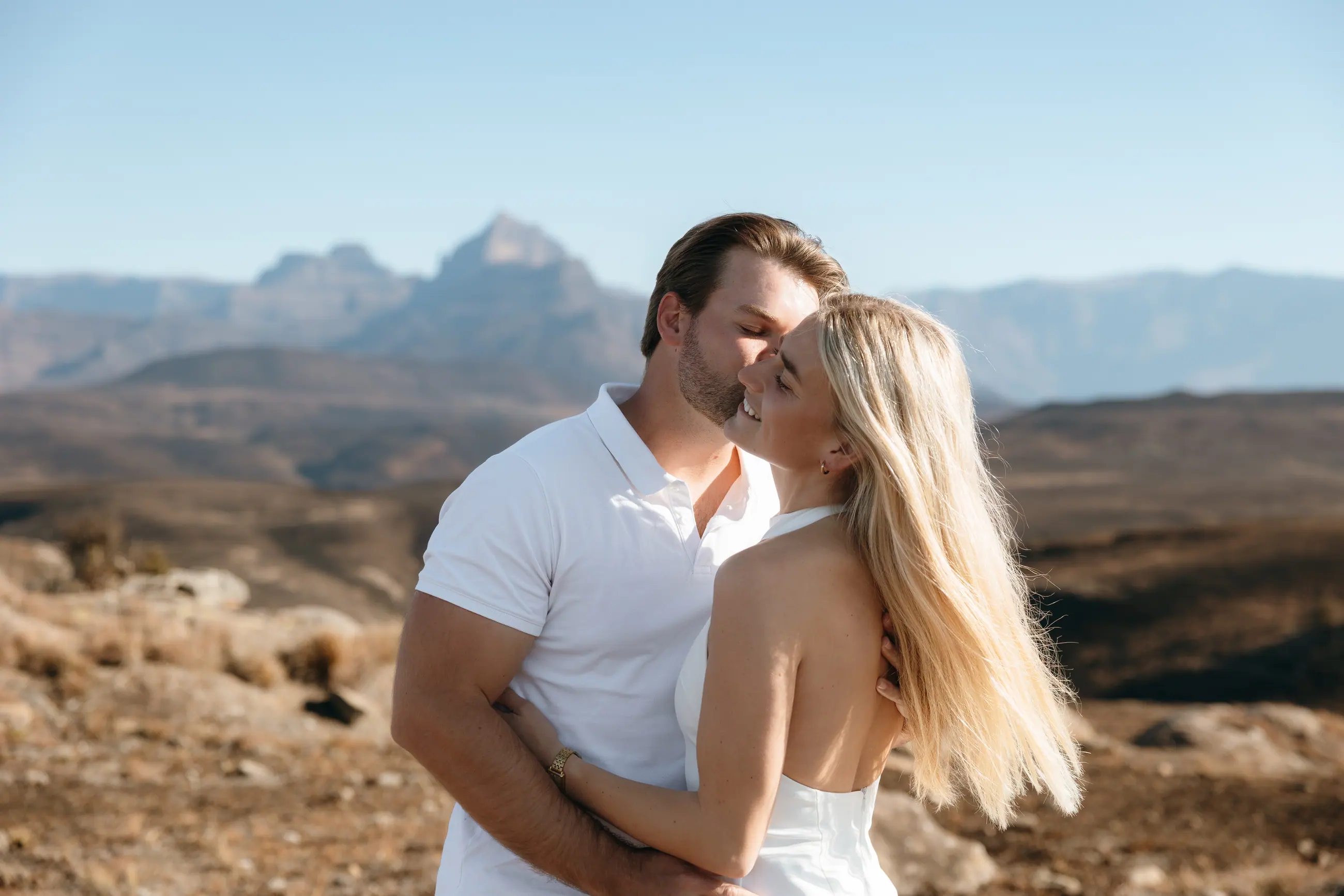 Christy and Joshua close together, laughing, the Drakensberg soft behind them